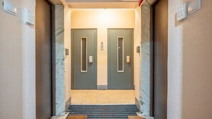 L’entrée d’un hôtel, avec deux portes, un clavier de sécurité et un escalier recouvert de moquette.