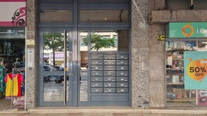 Ein Schaufenster mit einer grauen Metalldür, Kleidung in bunten Farben zur Schau gestellt, und ein Schild, das einen 50%-igen Rabatt anzeigt.