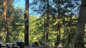 Ein Campingplatz mit Picknicktischen, Grill und Stühlen.