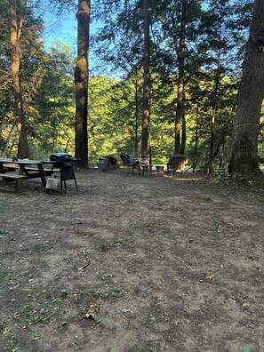 Ein Campingplatz mit Picknicktischen, Grill und Stühlen.