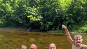 Eine Gruppe von Menschen in einer natürlichen Wasserlandschaft, umgeben von viel Grün.