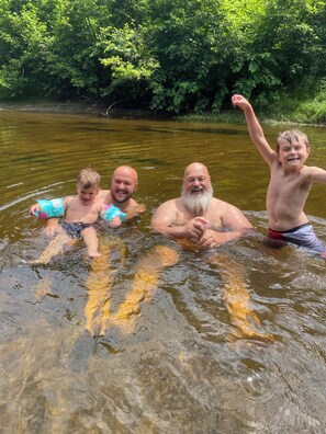 Eine Gruppe von Menschen in einer natürlichen Wasserlandschaft, umgeben von viel Grün.