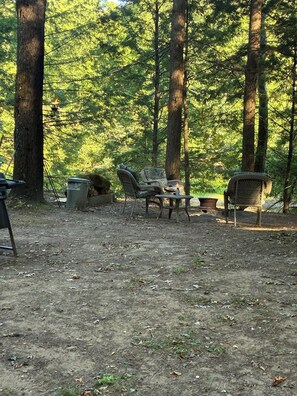 A forested campsite with outdoor seating and a fire pit. - Gorgeous 2-bedroom cabin in charming Camden for a relaxing getaway on fish creek (Camden)