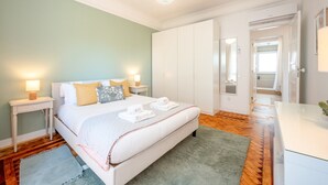 Et hotelværelse med en seng, to sengeborde, et spejl, et badeværelse der kan ses gennem en åben dør og et grønt tæppe.