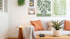 En stue med sofa, sofabord, lampe og billedkunst på væggen.