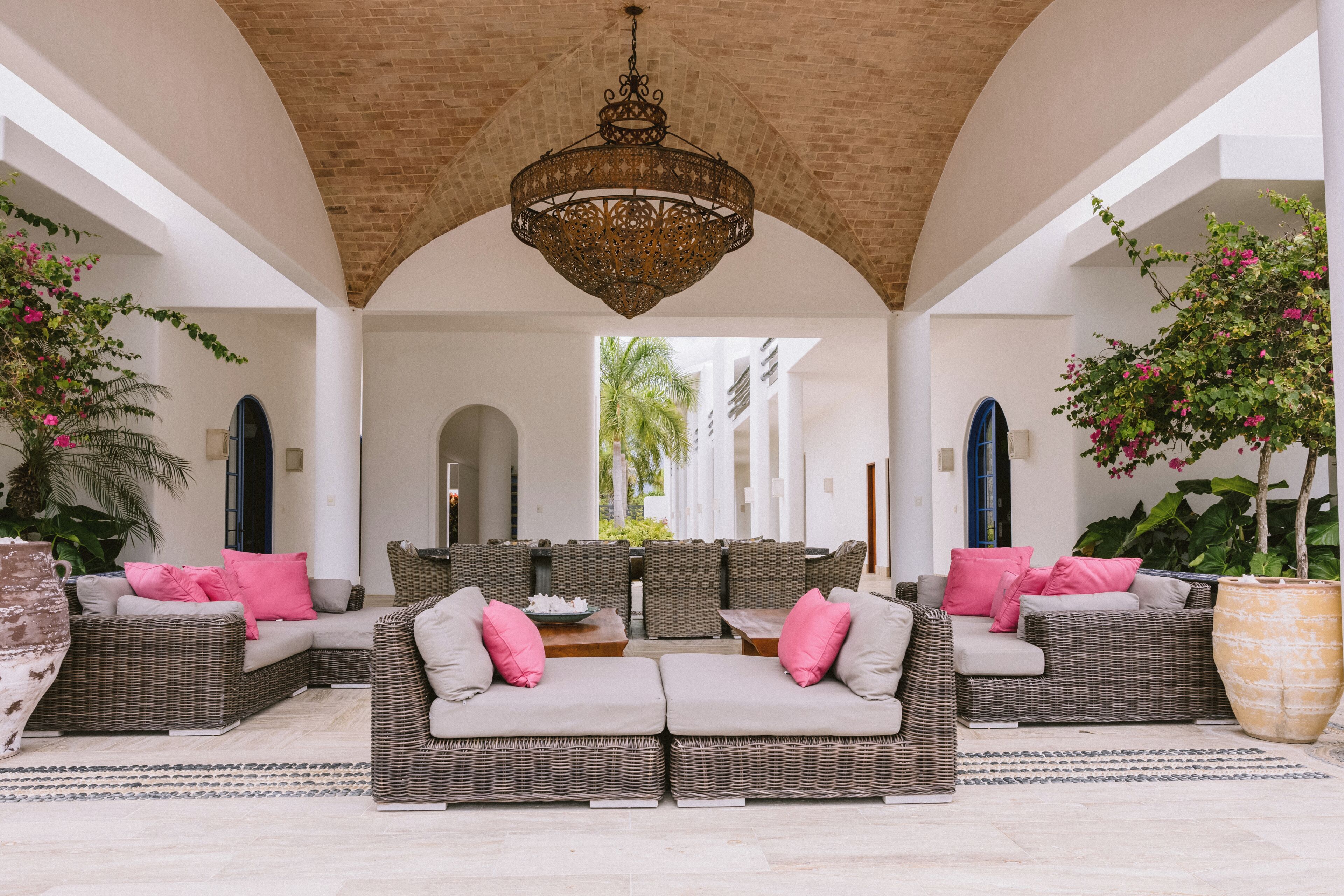 A covered outdoor seating area with wicker furniture and a central chandelier.