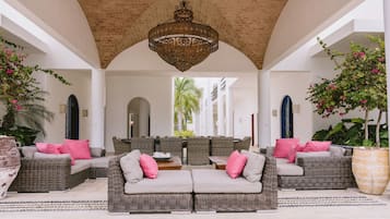 A covered outdoor seating area with wicker furniture and a central chandelier.
