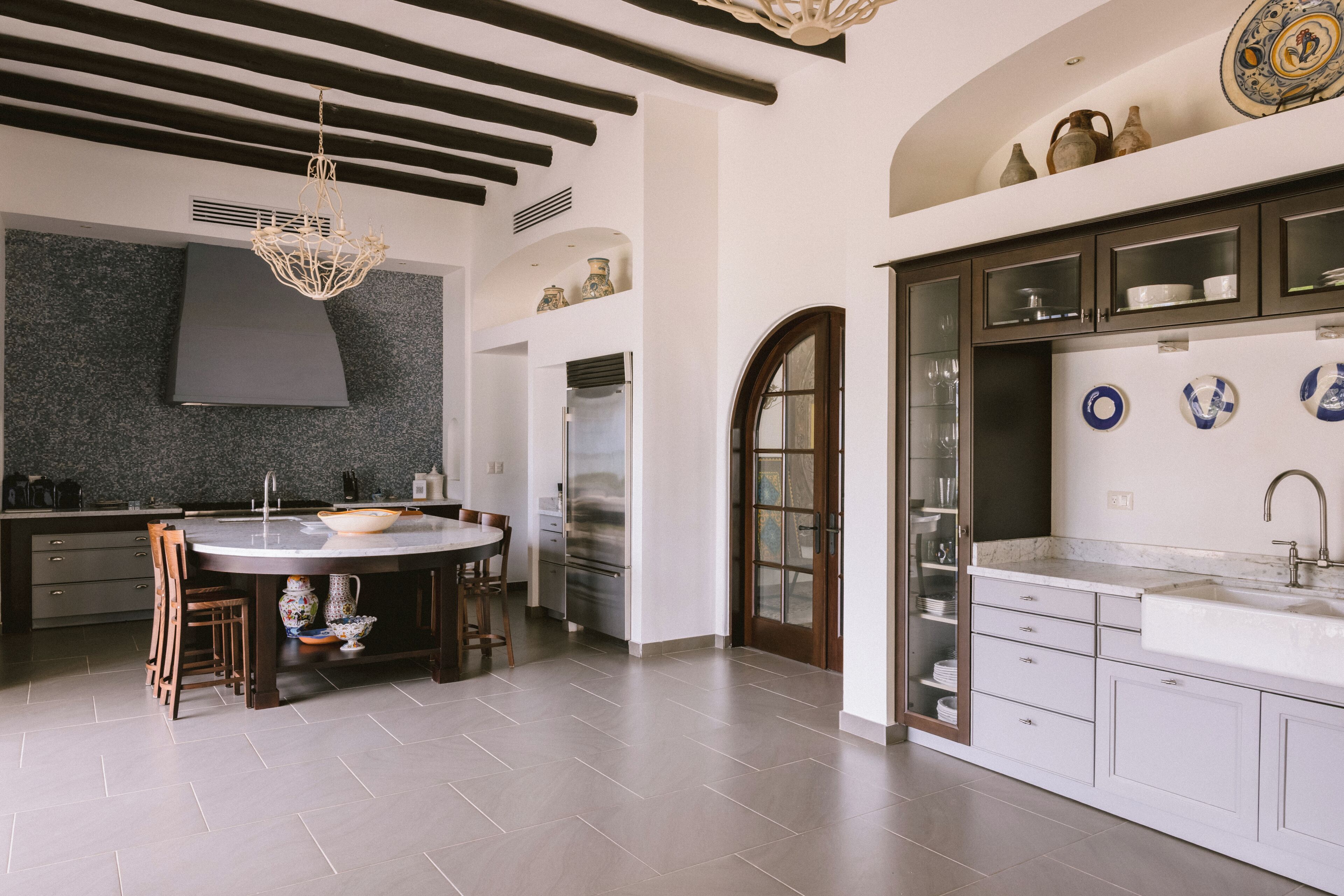 A modern kitchen with a central island, dark cabinetry, and a decorative ceiling light.