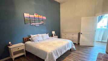 A bedroom with a bed, nightstands, a ceiling fan, and a door.