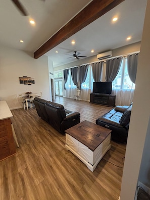 A spacious living area with a sofa set, a coffee table, and a television.