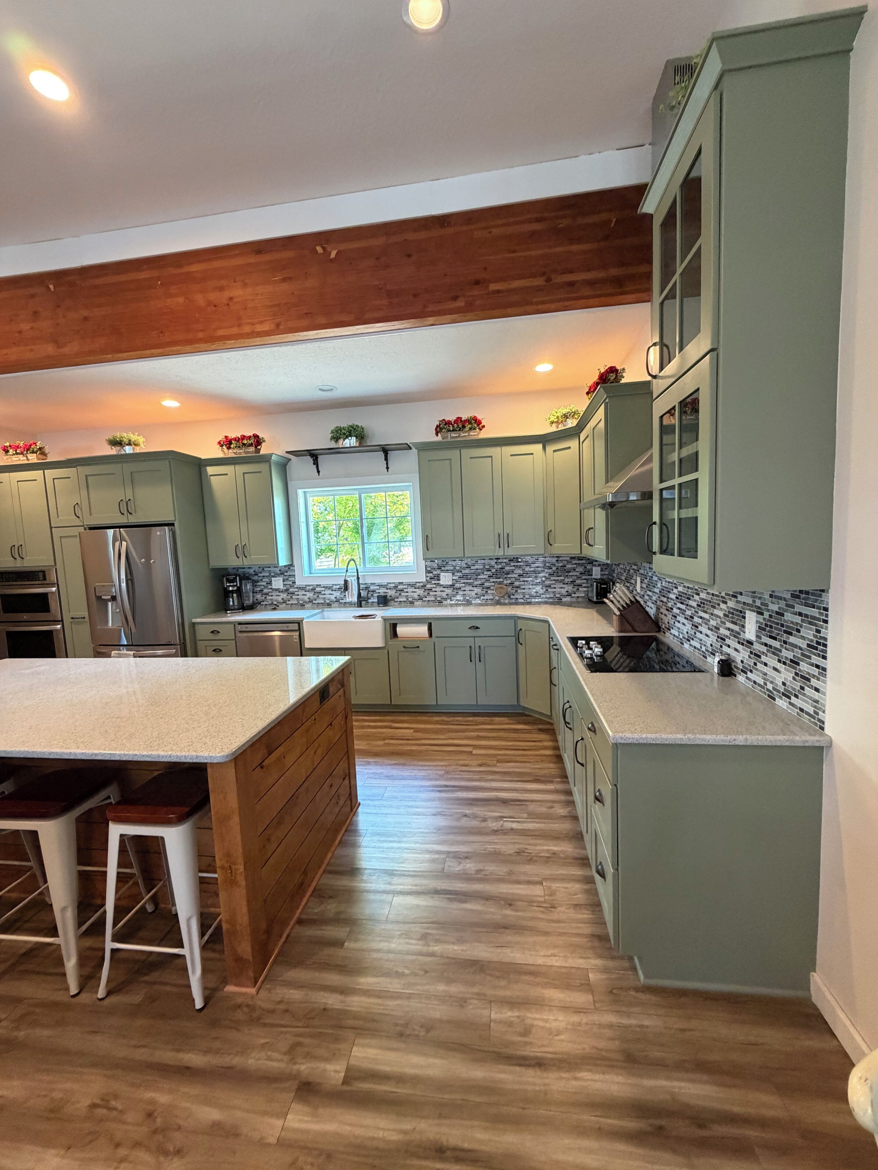 A kitchen with green cabinets, a wooden island, and a window.