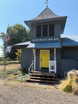 A building with a yellow door, labeled 'DISTRICT NO. 20,' and a small porch with steps leading up to it.