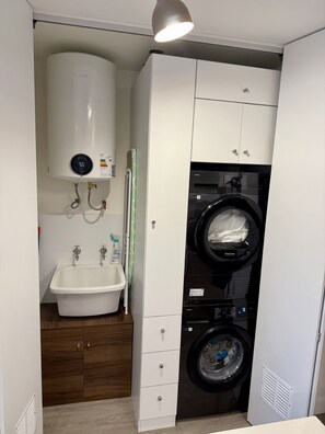 Un baño pequeño con lavadora integrada, lavamanos e inodoro.