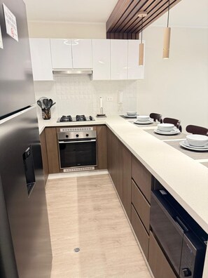 A modern kitchen with a stainless steel refrigerator, a built-in oven, a stove, and a dishwasher. - Beautiful 3-bedroom apartment in delightful Miraflores neighborhood (Miraflores)