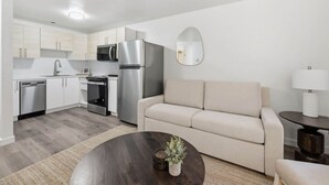Eine moderne Küche mit Edelstahlgeräten, ein Essbereich mit einem runden Tisch und eine Sitzecke mit einer Couch.