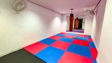 A hallway with a red and blue interlocking floor, a white wall, and a ceiling fan.