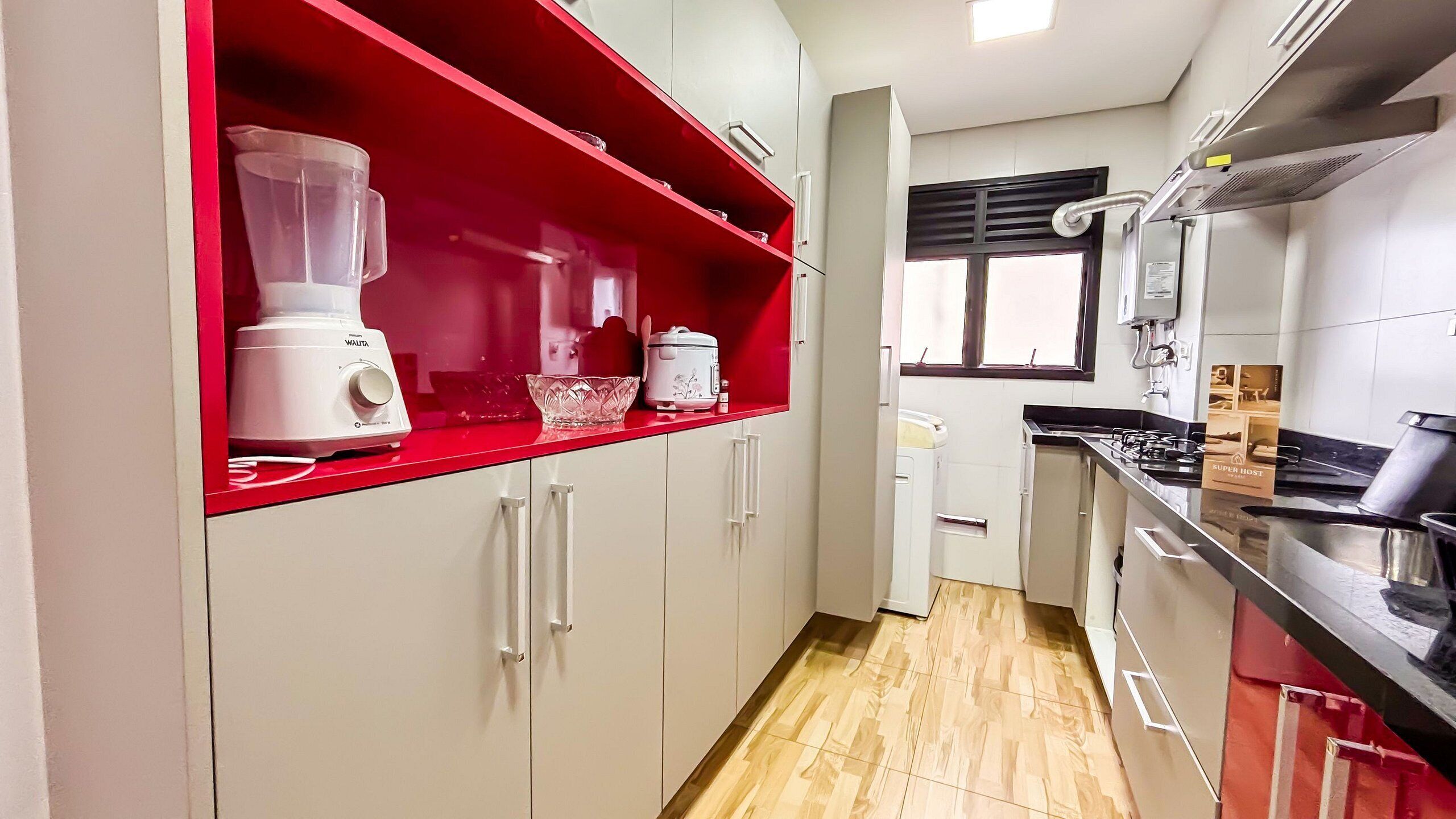 Una cocina con un estante rojo, una licuadora, una olla de cocción lenta y una estufa.