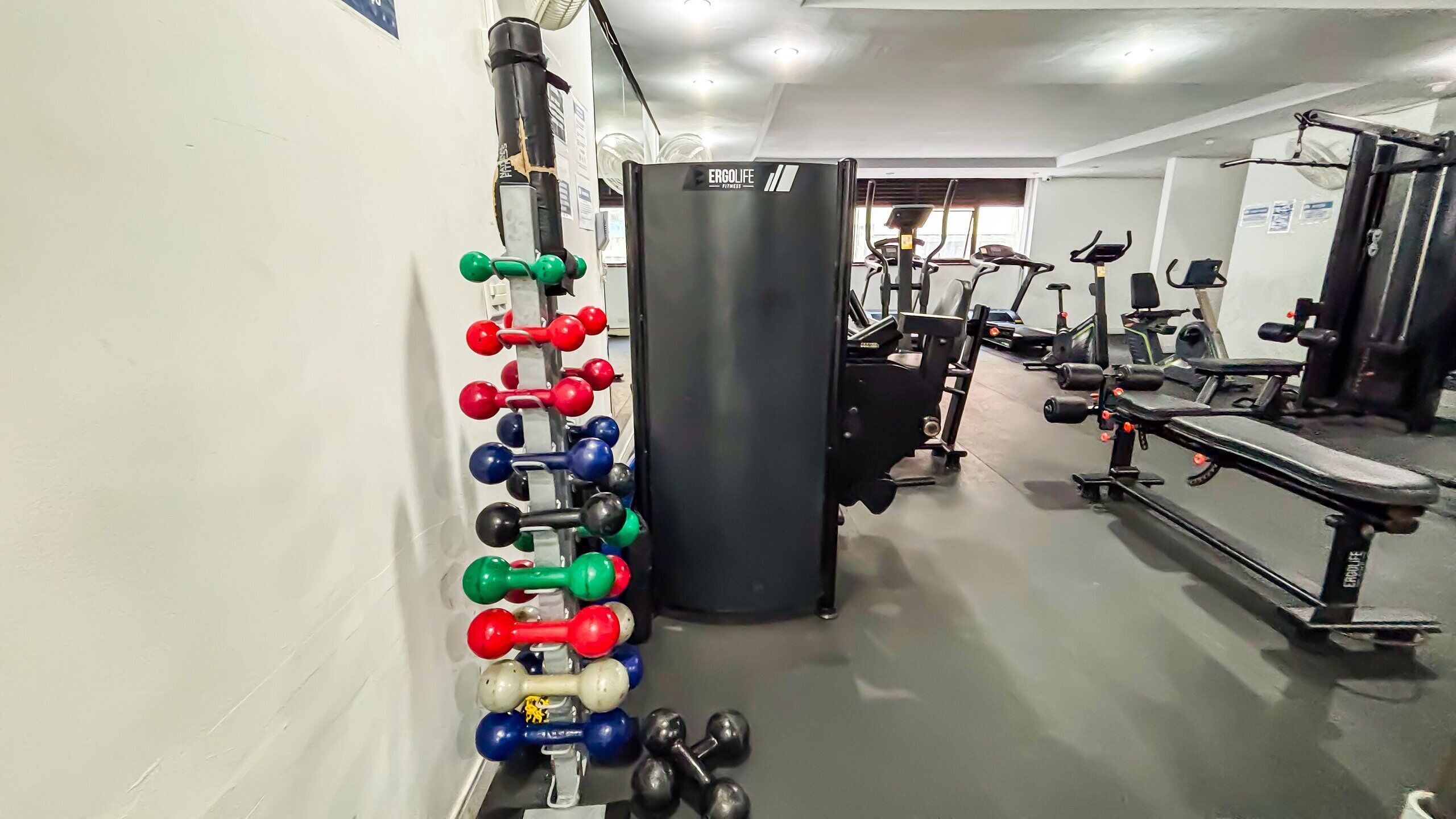 Un gimnasio con diversos equipos de ejercicio, incluyendo mancuernas, un saco de boxeo y máquinas de cardio.