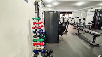 Un gimnasio con diversos equipos de ejercicio, incluyendo mancuernas, un saco de boxeo y máquinas de cardio.