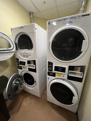 Eine Waschküche mit vier Waschmaschinen, jede mit digitalem Display und Bedienfeld.