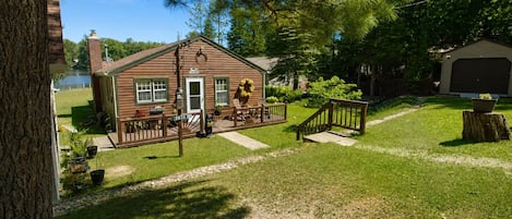 Eine Holzhütte mit Veranda, einem eingezäunten Hof und einer Garage.