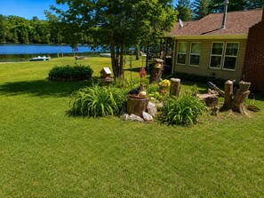 A well-maintained lawn with a bird feeder, a small pond with a boat, and a house with a satellite dish.