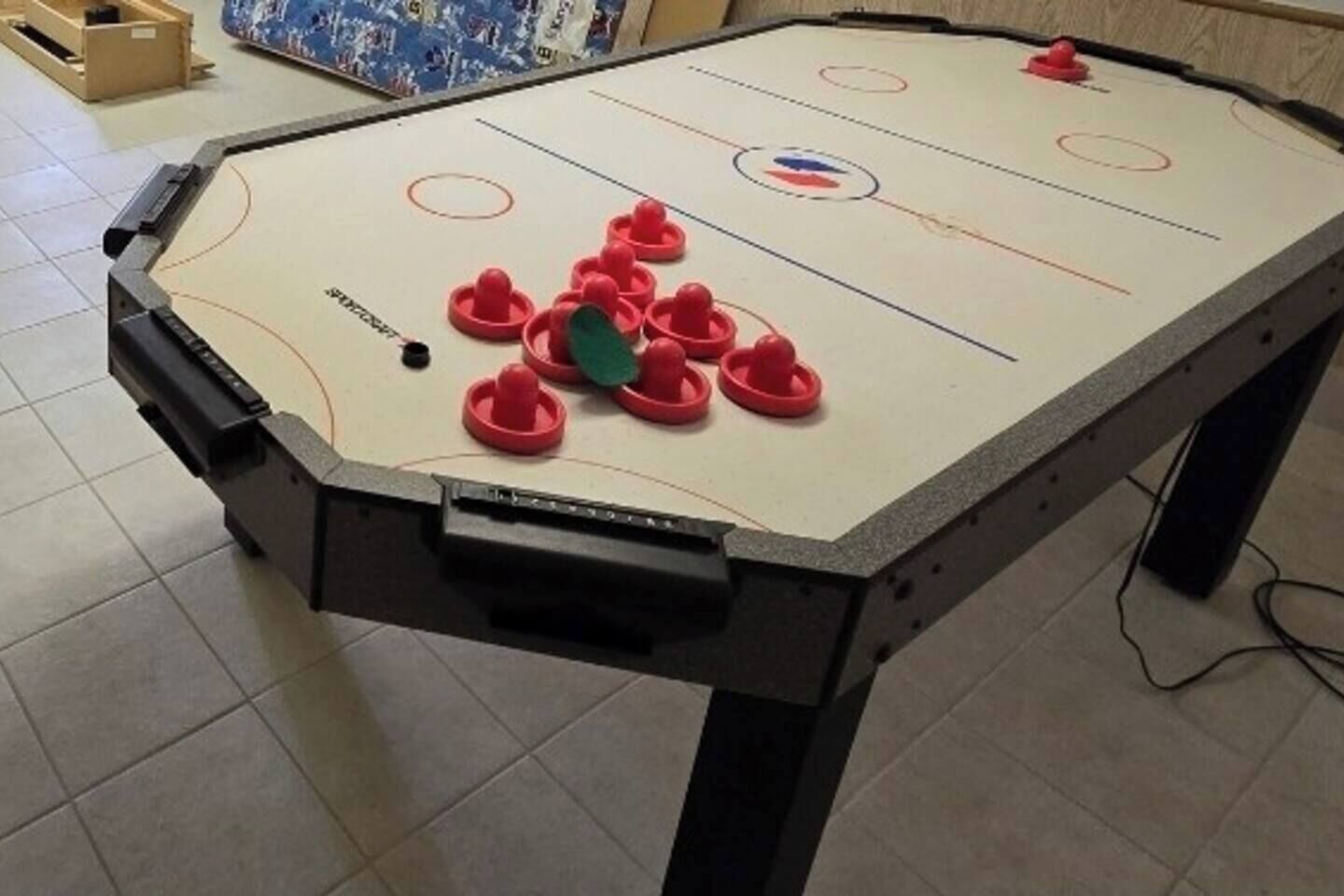 Et bord med en ishockeypuck og røde og grønne pucks, en træramme og et flisegulv.
