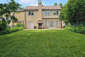 Une maison à deux étages avec une pelouse bien entretenue, une cheminée et une porte d’entrée.