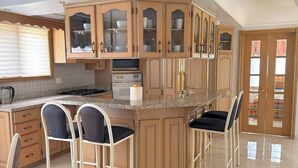 A kitchen with a central island, bar stools, a stove, oven, and cabinets.
