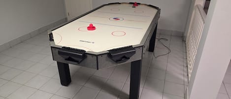 A foosball table with a Sportcraft logo, located in a room with white tiled flooring and a white door in the background.