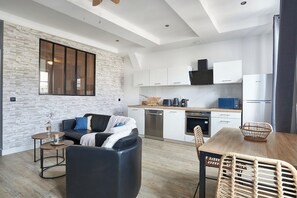 A modern kitchen with white cabinets, a black range hood, and a built-in oven.
