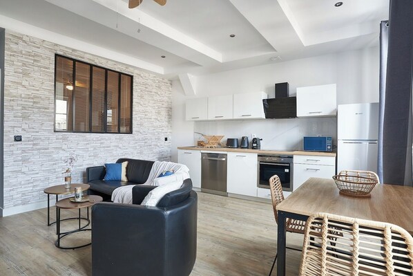 A modern kitchen with white cabinets, a black range hood, and a built-in oven.