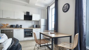 A modern kitchen with white cabinets, a dining table with chairs, and a large window with curtains.