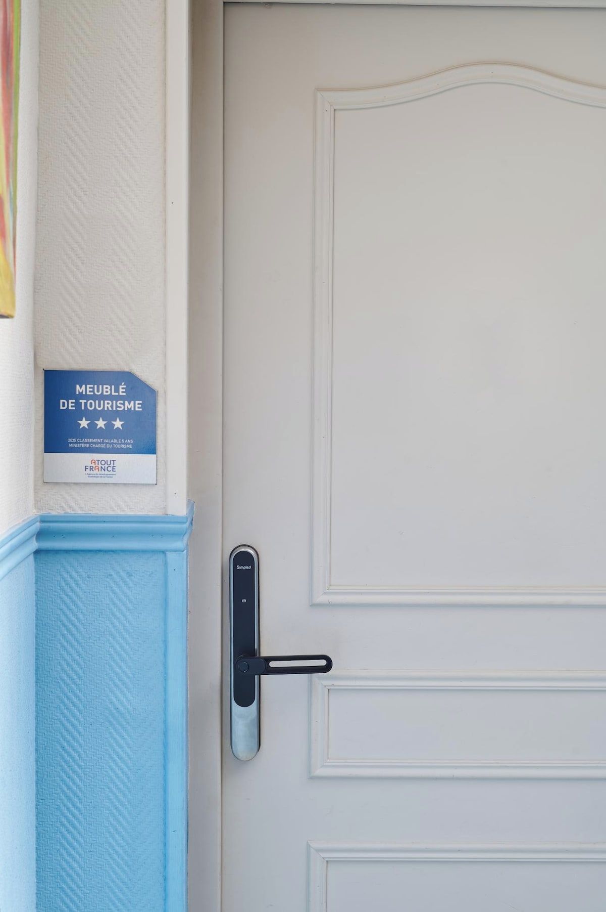 Une porte dotée d’un panneau bleu texturé, d’une poignée de porte et d’une plaque indiquant qu’elle a reçu un prix dans le domaine du tourisme.