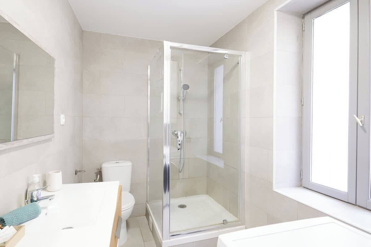Une salle de bain moderne avec une douche à parois de verre, des toilettes et un lavabo.