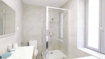 Une salle de bain moderne avec une douche à parois de verre, des toilettes et un lavabo.