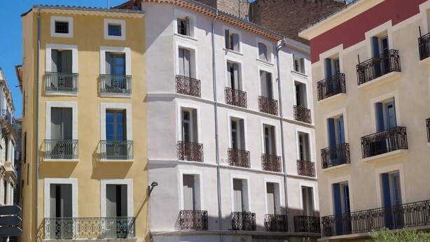 A multi-story building with balconies, a clear sky, and adjacent buildings. - Cozy stay place de la Madeleine (Béziers)