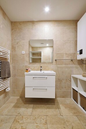 Een moderne badkamer met een wit wastafelmeubel, een spiegel en een handdoekrek.