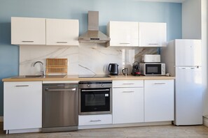 A modern kitchen with white cabinets, a stainless steel dishwasher, an oven, a microwave, and a refrigerator. - Elegant flat with Les Halles View & AC (Béziers)