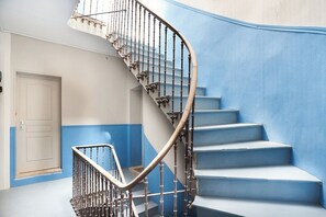 A spiral staircase with a metal railing, leading to a landing with a white door. - Elegant flat with Les Halles View & AC (Béziers)