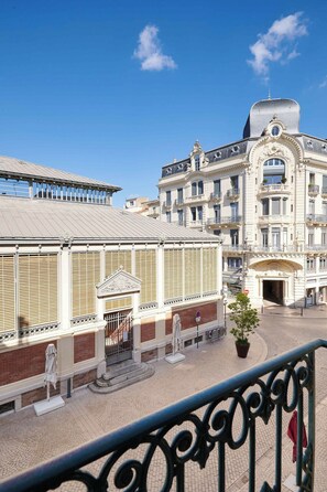 Un edificio histórico con arquitectura ornamentada, un espacio de estar al aire libre cubierto y un patio empedrado.