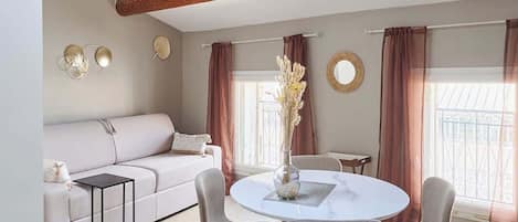 A modern living room with a skylight, wooden beams, a round dining table, and a sofa.