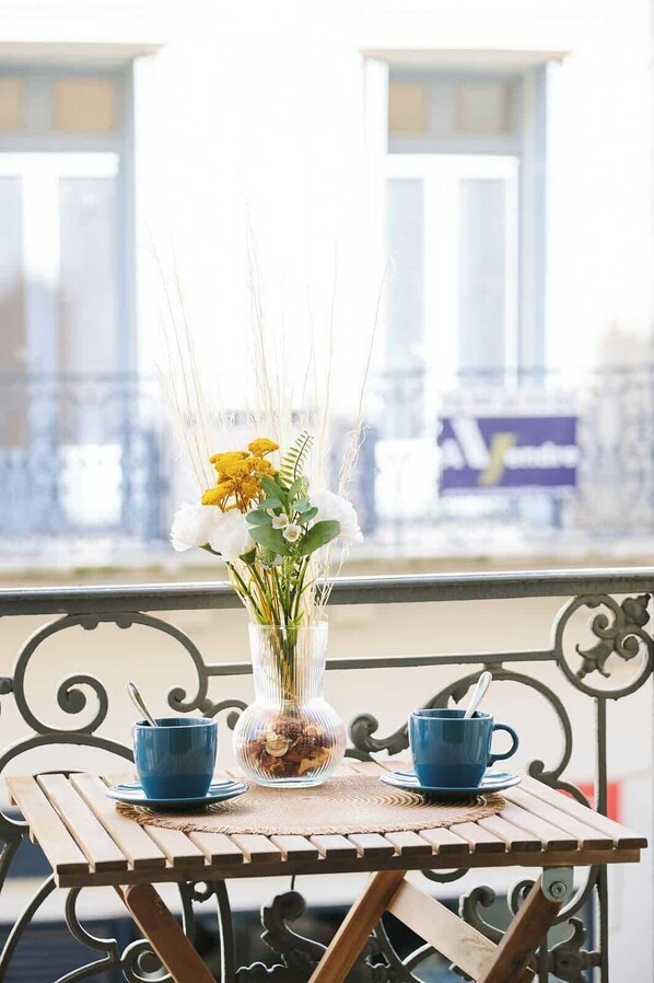 A table with a vase of flowers and two blue cups on a balcony. - Prestige Halles View Balcony and AC (Béziers)