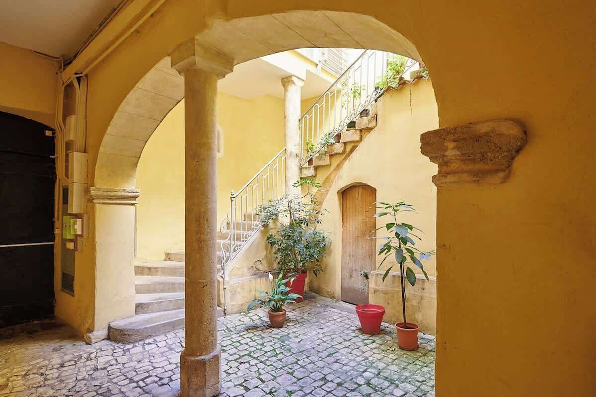 Ein gewölbter Gang mit Treppe, Topfpflanzen und einer Tür.