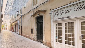 Una calle adoquinada con un edificio que muestra un letrero que dice 'Le Petit Ma Restaurant'.