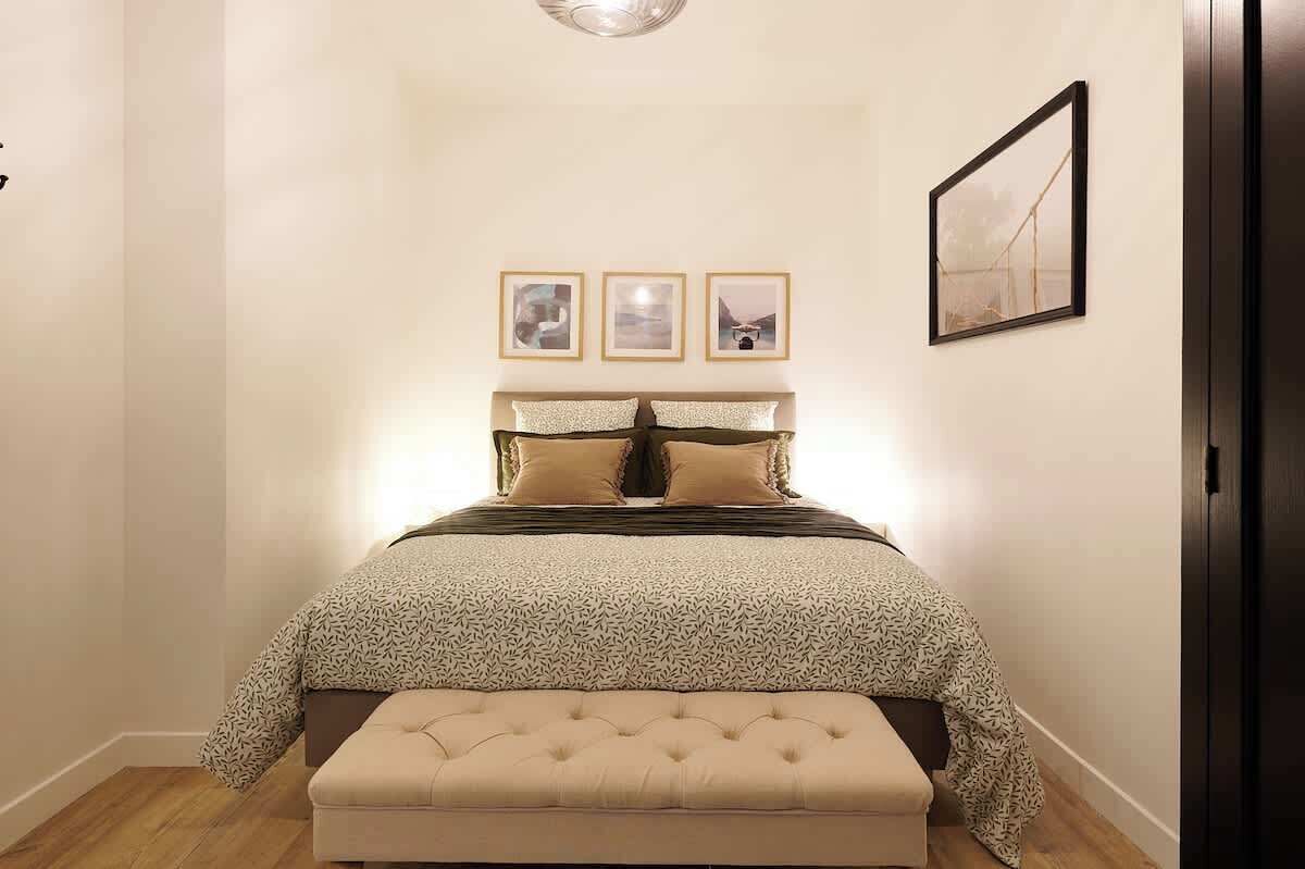 Ein Schlafzimmer mit einem Bett, einer Bank und drei gerahmten Bildern an der Wand.
