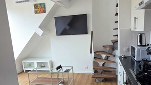 Una cocina moderna con televisión de pantalla plana, suelo de madera y horno empotrado.