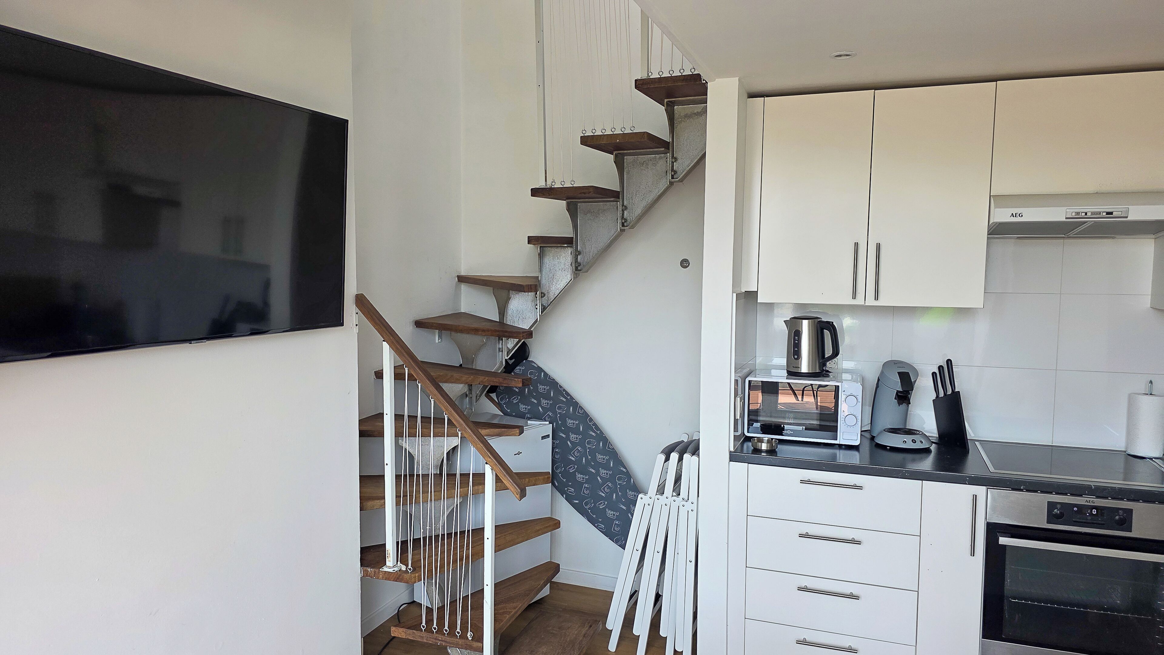 A modern kitchen with white cabinets, a built-in oven, a coffee maker, and a microwave.