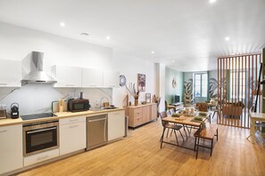 A modern kitchen with a dining area, wooden flooring, and a view of the living room. - Historic Béziers Apt: AC, Balcony, Market View (Béziers)