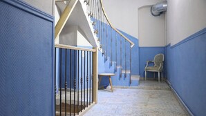Eine Treppe mit Metallgeländer, ein Stuhl und eine Wand in Blau-Weiß gehalten.